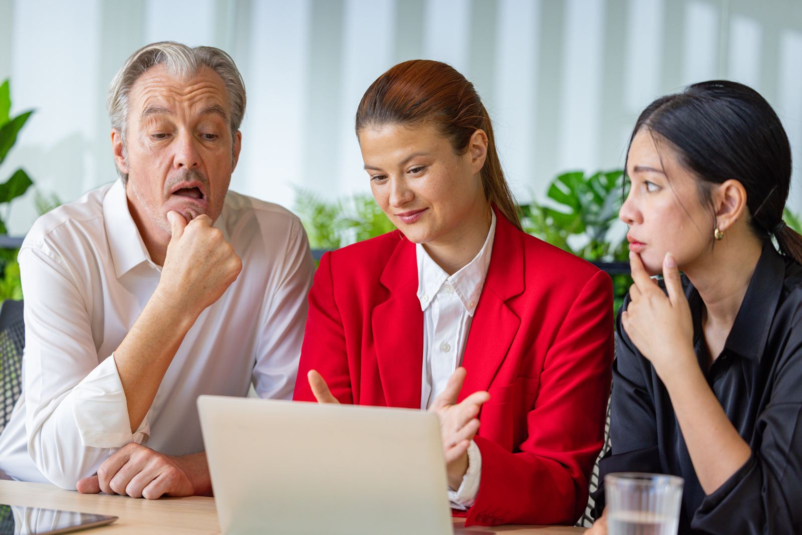 Three colleagues looking sceptically at a laptop screen together
