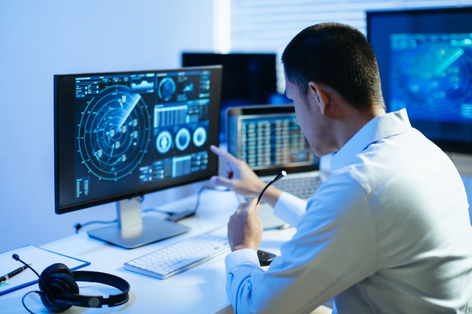 A man working at several screens showing real-time data dashboards