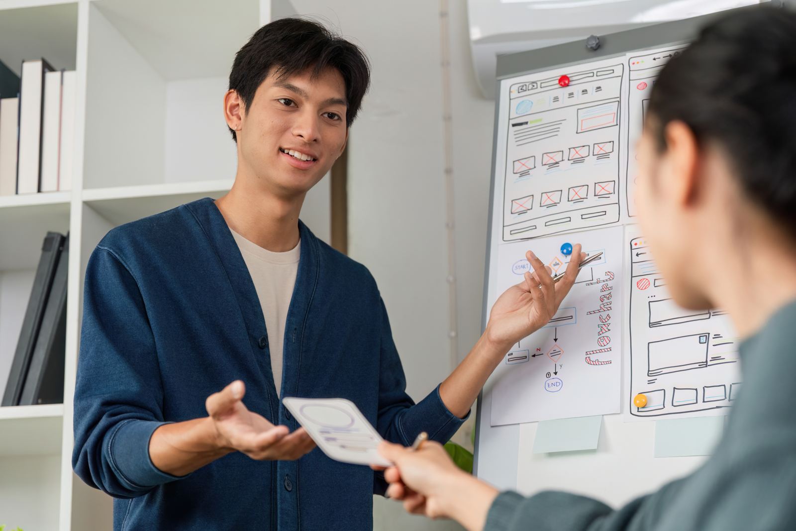 A man explaining wireframes on a whiteboard to a colleague