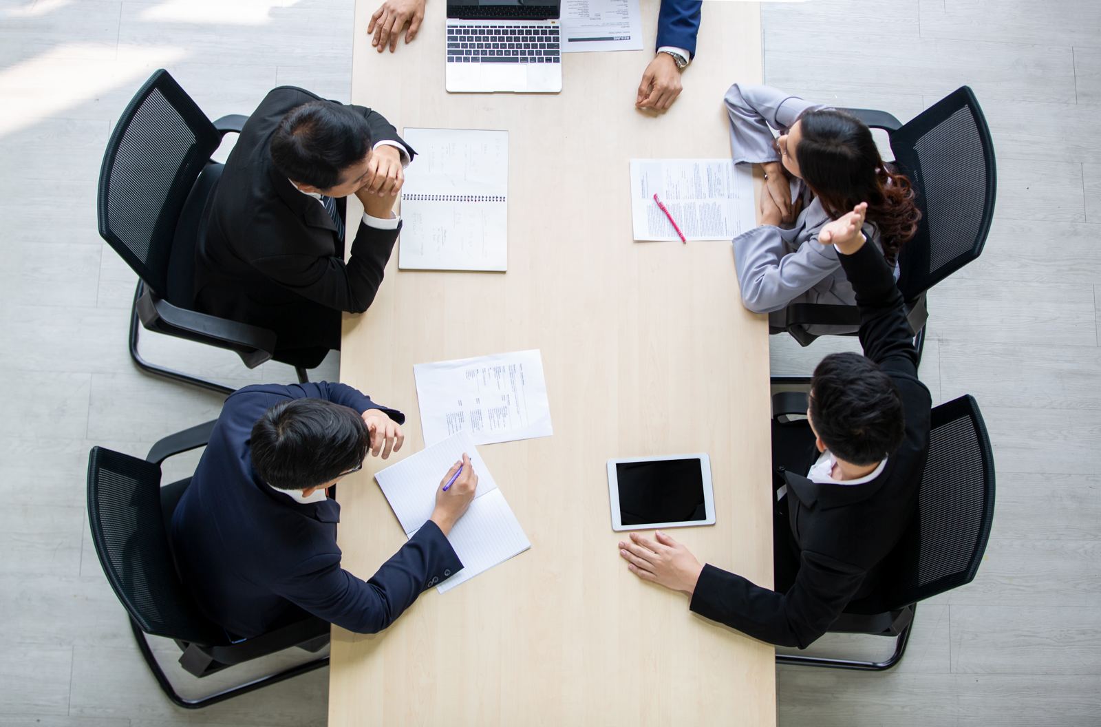 Four colleagues seen from above at a meeting table, working through printed documents